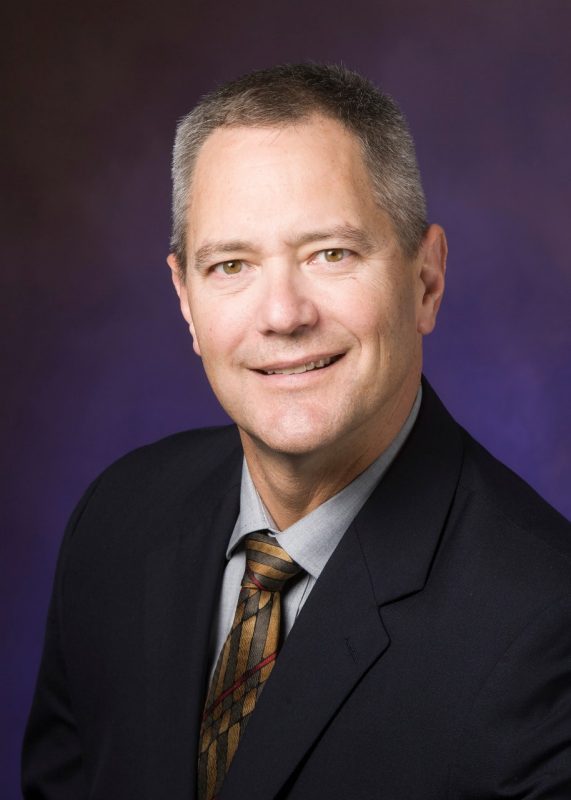 Kevin Pitts poses for a photo wearing a dark suit