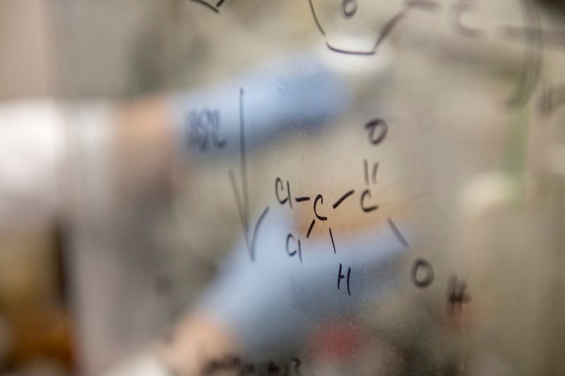 A pair of  hands, wearing blue gloves, are inside a chemistry hood as the person prepares and analyzes samples of a polymer called PEEK.  