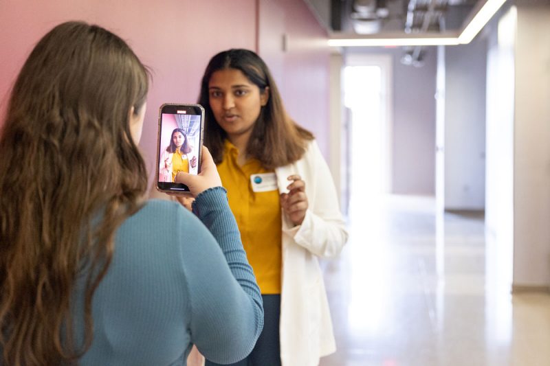 Student in background being filmed by a smart phone, which is in the foreground